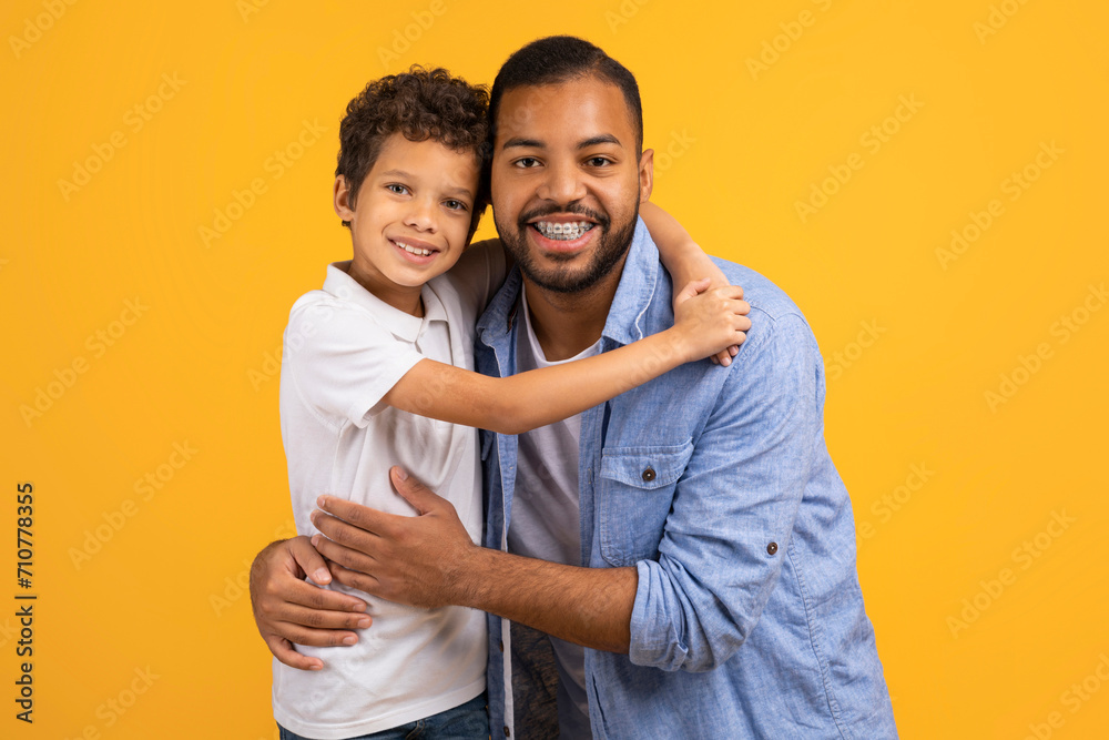 Affectionate black father and little son embracing with joyful smiles Affectionate black father and little son embracing with joyful smiles