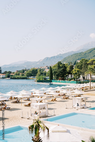 Sandy beach with swimming pools  sun loungers and sun umbrellas on the seashore