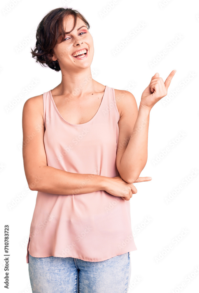 Beautiful young woman with short hair wearing casual style with sleeveless shirt with a big smile on face, pointing with hand and finger to the side looking at the camera. Beautiful young woman with short hair wearing casual style with sleeveless shirt with a big smile on face, pointing with hand and finger to the side looking at the camera.