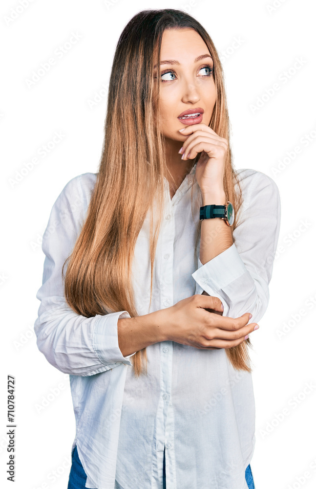 Beautiful caucasian woman wearing casual white shirt with hand on chin thinking about question, pensive expression. smiling and thoughtful face. doubt concept. Beautiful caucasian woman wearing casual white shirt with hand on chin thinking about question, pensive expression. smiling and thoughtful face. doubt concept.