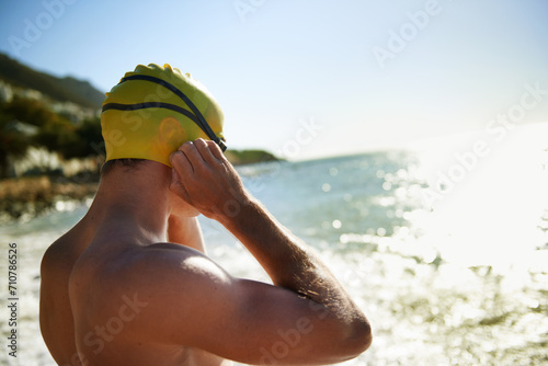 Sea, beach and man for swimmer exercise, nature workout or outdoor practice in ocean, sea or water waves. Swimwear, swimming cap and athlete prepare to start challenge, fitness performance or cardio #710786526