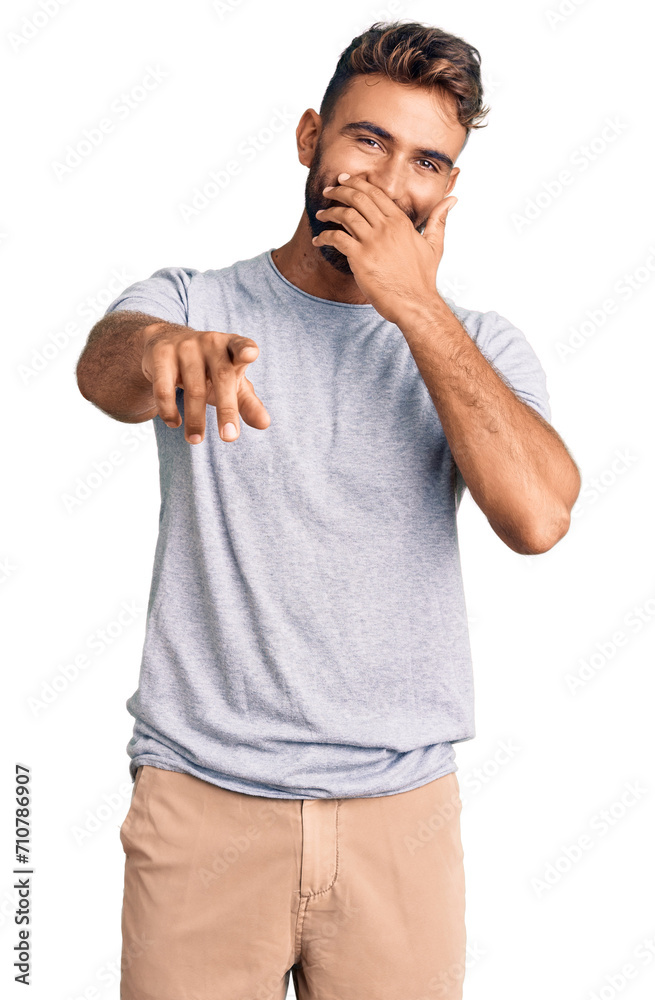 Young hispanic man wearing casual clothes laughing at you, pointing finger to the camera with hand over mouth, shame expression Young hispanic man wearing casual clothes laughing at you, pointing finger to the camera with hand over mouth, shame expression