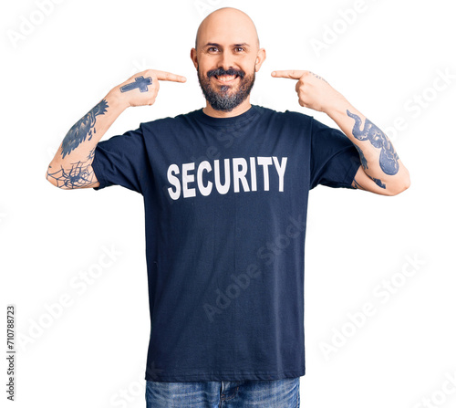 Young handsome man wearing security t shirt smiling cheerful showing and pointing with fingers teeth and mouth. dental health concept.