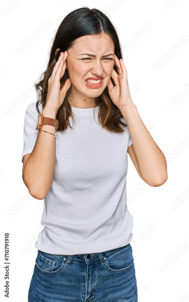 Young beautiful woman wearing casual white t shirt covering ears with fingers with annoyed expression for the noise of loud music. deaf concept. Young beautiful woman wearing casual white t shirt covering ears with fingers with annoyed expression for the noise of loud music. deaf concept.