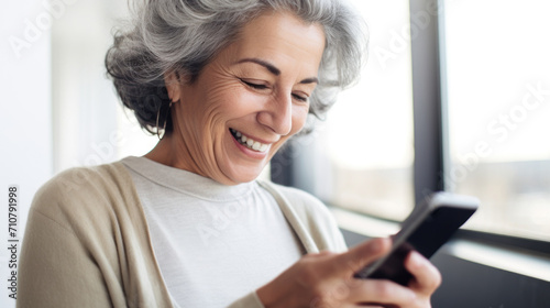 A senior woman looking at the smartphone and laughing closeup.