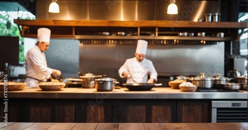 Empty Wooden table on blur chefs cooking in the kitchen background in Restaurant.