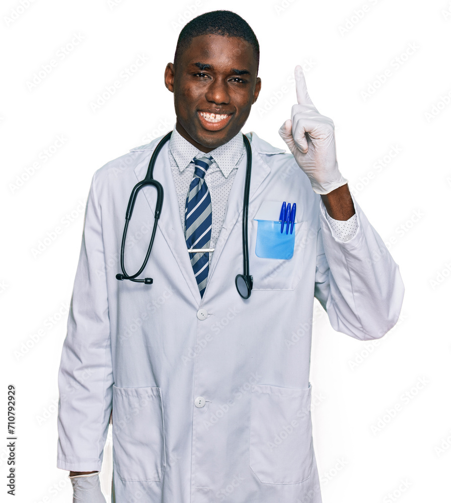 Young african american man wearing doctor uniform and stethoscope pointing finger up with successful idea. exited and happy. number one. Young african american man wearing doctor uniform and stethoscope pointing finger up with successful idea. exited and happy. number one.