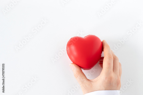 Female doctor holding red heart in hand isolated on white background. Top view. Copy space. Organ donation, healthcare, love, and medical support concept.