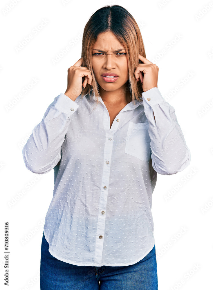 Young hispanic woman wearing casual white shirt covering ears with fingers with annoyed expression for the noise of loud music. deaf concept. Young hispanic woman wearing casual white shirt covering ears with fingers with annoyed expression for the noise of loud music. deaf concept.