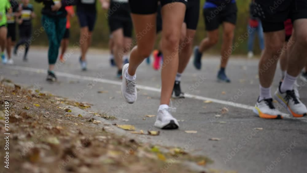 Focused on runners' feet, this image captures dynamic energy of marathon in progress amid the fallen leaves of autumn Focused on runners' feet, this image captures dynamic energy of marathon in progress amid the fallen leaves of autumn