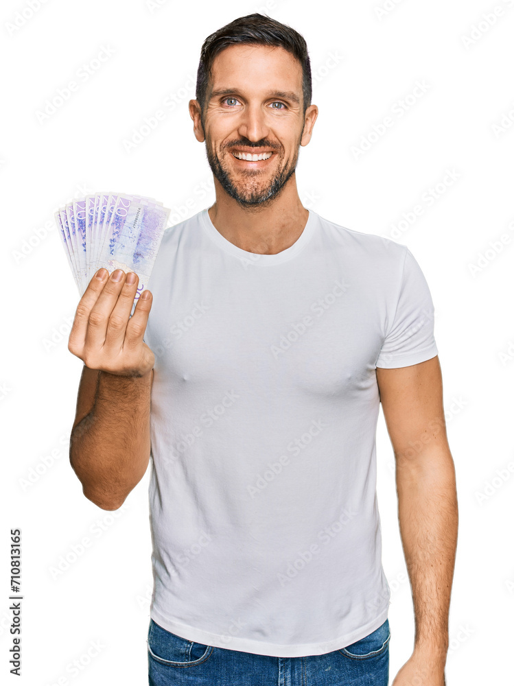 Handsome man with beard holding 20 swedish krona banknotes looking positive and happy standing and smiling with a confident smile showing teeth Handsome man with beard holding 20 swedish krona banknotes looking positive and happy standing and smiling with a confident smile showing teeth