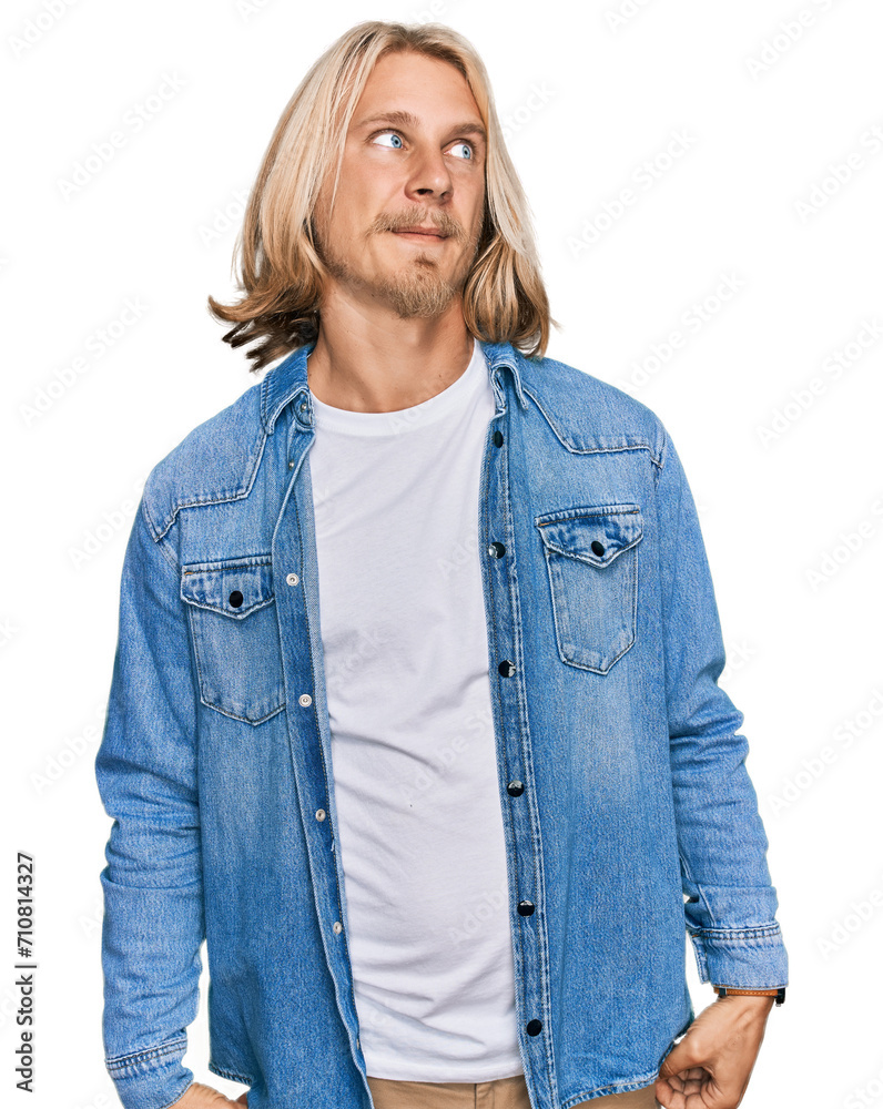 Caucasian man with blond long hair wearing casual denim jacket smiling looking to the side and staring away thinking. Caucasian man with blond long hair wearing casual denim jacket smiling looking to the side and staring away thinking.