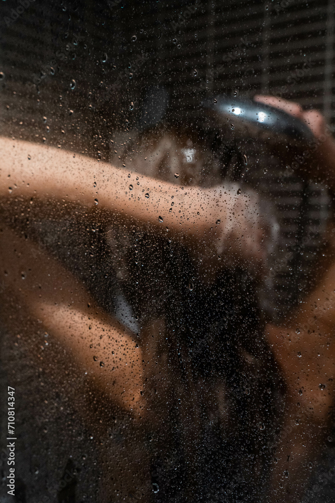Rear view of blonde woman rinsing her hair inside the shower in the bathroom