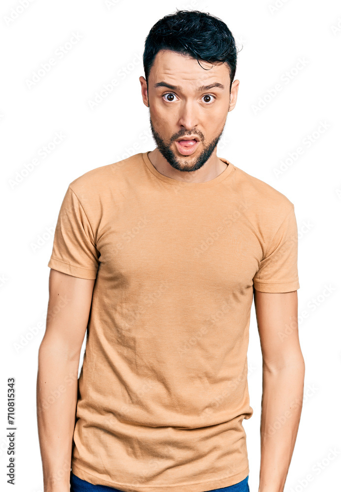 Fototapeta premium Hispanic man with beard wearing casual t shirt in shock face, looking skeptical and sarcastic, surprised with open mouth