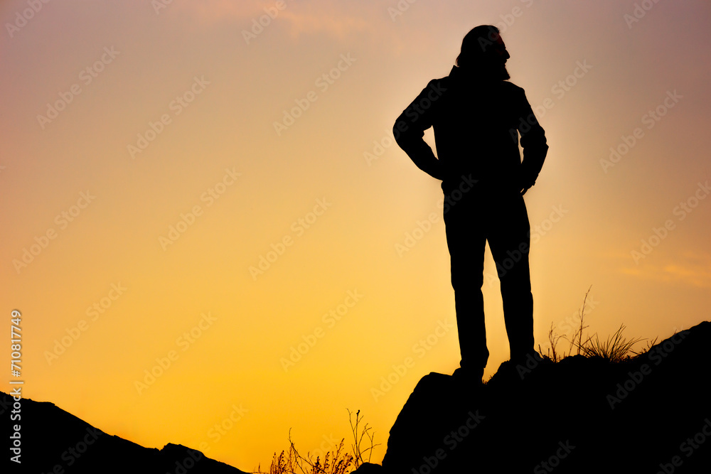 the silhouette of a man on an orange background, the man looks back
