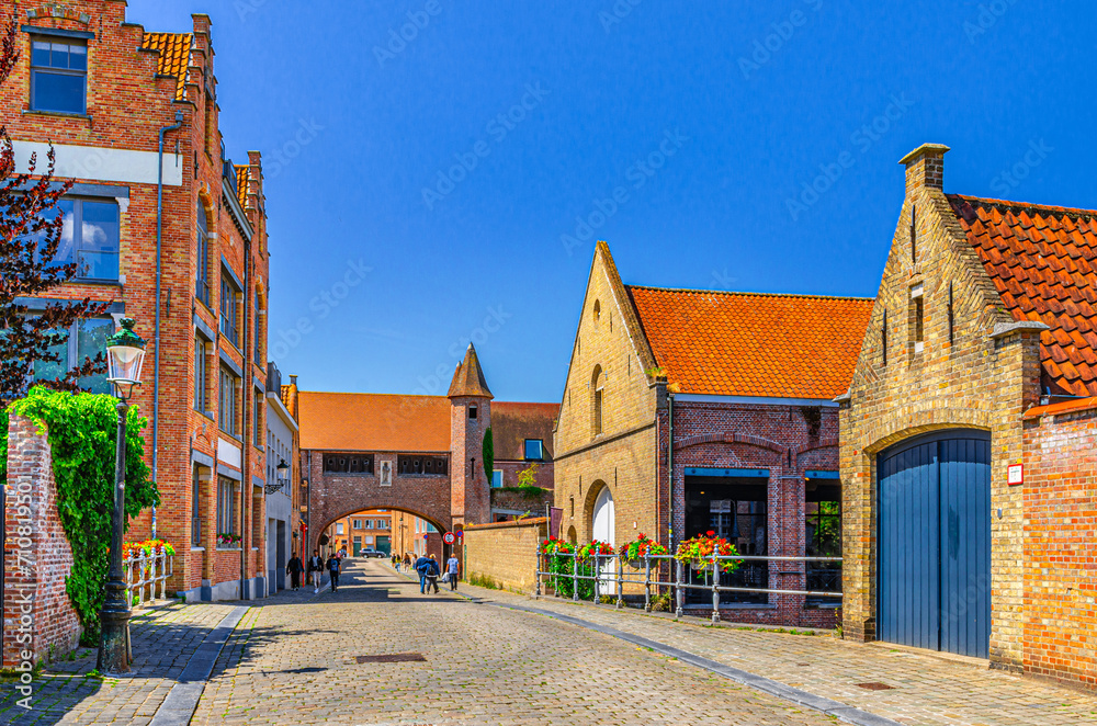 Bruges cityscape with buildings of Art Gallery Koetshuis and Zonnekemeers Gate with brick walls in Brugge city historical centre, Bruges old town quarter medieval district, Flemish Region, Belgium