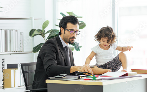 Caucasian handsome father wearing eyeglasses, working at home, playing and taking care of his little daughter. Parenthood and New Normal Concept.
