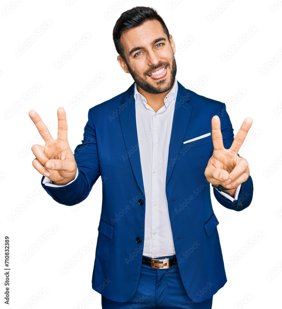 Young hispanic man wearing business jacket smiling with tongue out showing fingers of both hands doing victory sign. number two. Young hispanic man wearing business jacket smiling with tongue out showing fingers of both hands doing victory sign. number two.