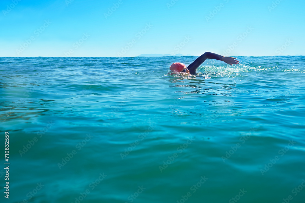 Swimming, stroke and person in ocean water in summer for exercise, training or workout on mockup space. Sea, sport and a young athlete outdoor for fitness, health and triathlon competition in nature