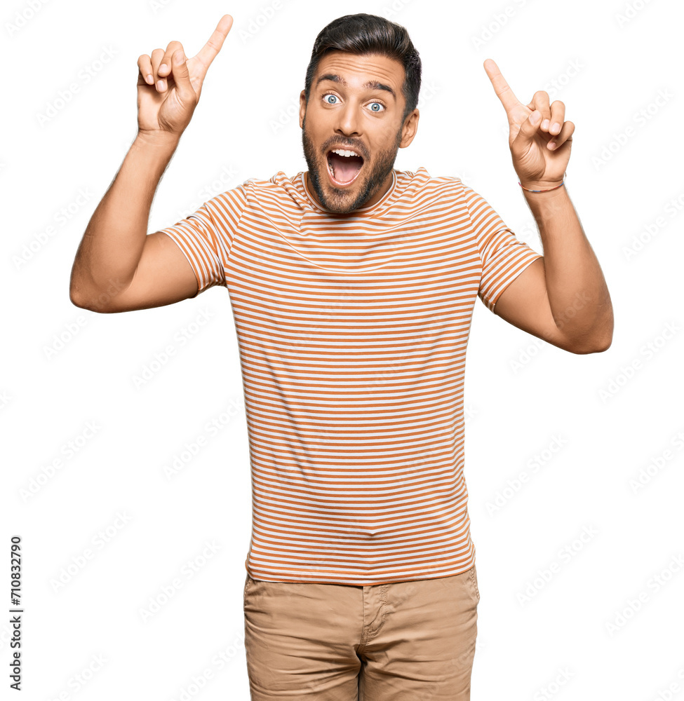 Fototapeta premium Handsome hispanic man wearing casual clothes smiling amazed and surprised and pointing up with fingers and raised arms.