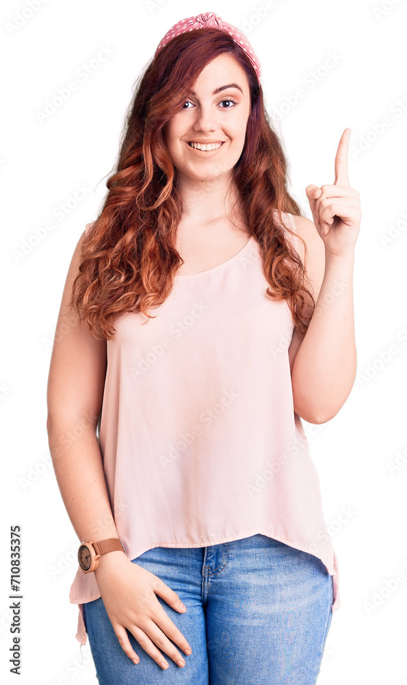 Young beautiful woman wearing casual clothes and diadem pointing finger up with successful idea. exited and happy. number one. Young beautiful woman wearing casual clothes and diadem pointing finger up with successful idea. exited and happy. number one.
