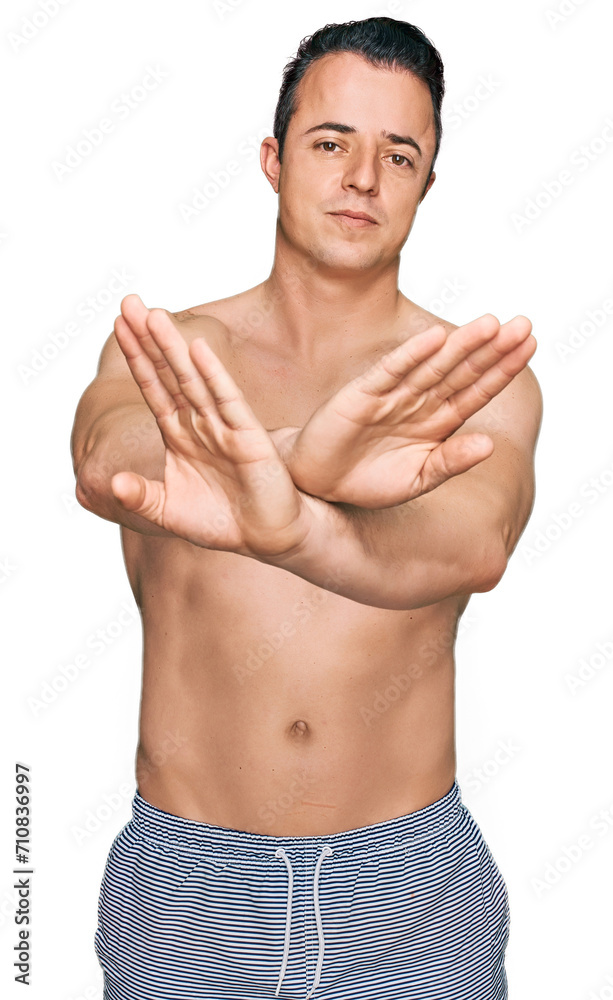Fototapeta premium Handsome young man wearing swimwear shirtless rejection expression crossing arms doing negative sign, angry face