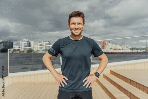 Fit man resting after workout with cityscape background.