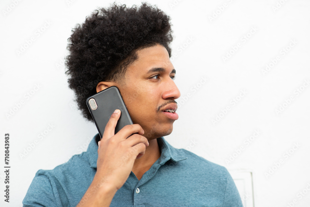 © mimagephotos - young man talking with cellphone by white background