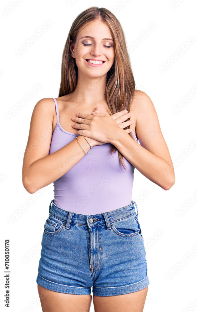 Young beautiful blonde woman wearing casual style with sleeveless shirt smiling with hands on chest with closed eyes and grateful gesture on face. health concept.