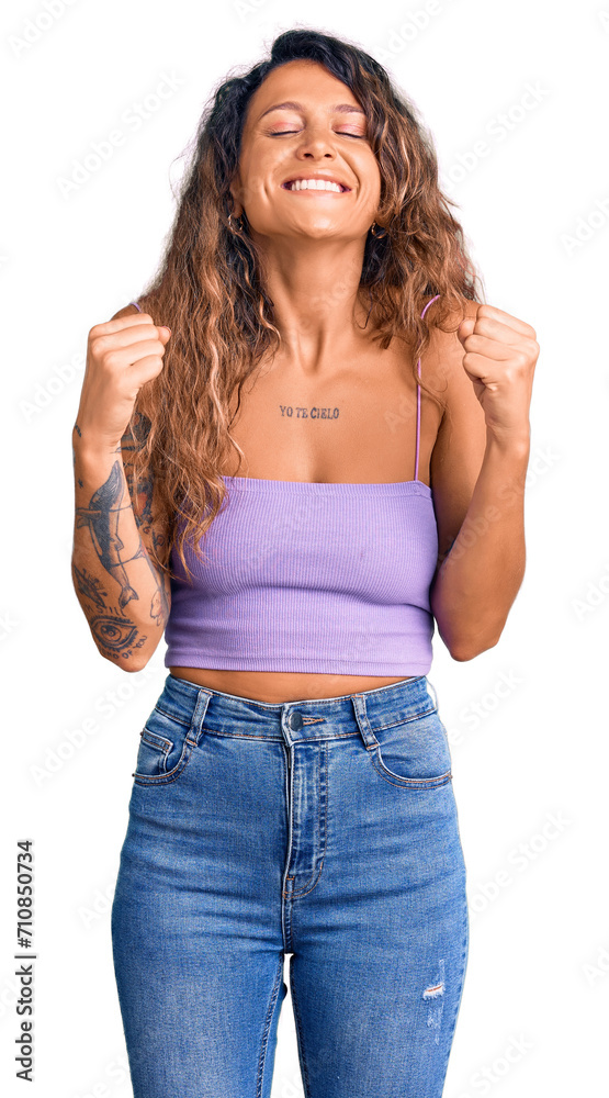 Young hispanic woman with tattoo wearing casual clothes excited for success with arms raised and eyes closed celebrating victory smiling. winner concept. Young hispanic woman with tattoo wearing casual clothes excited for success with arms raised and eyes closed celebrating victory smiling. winner concept.
