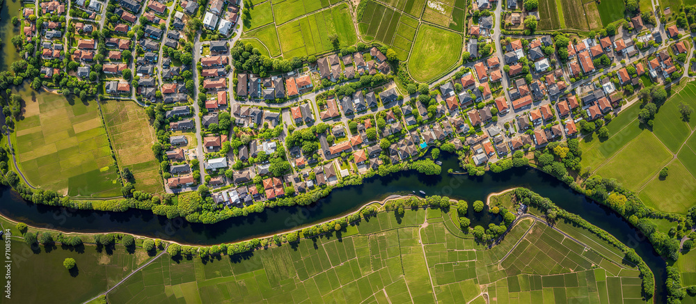 Obraz premium Banner of aerial satellite view of cultivated agricultural farming land fields with vivid green color as a typical European or countryside farmland village town with canal river