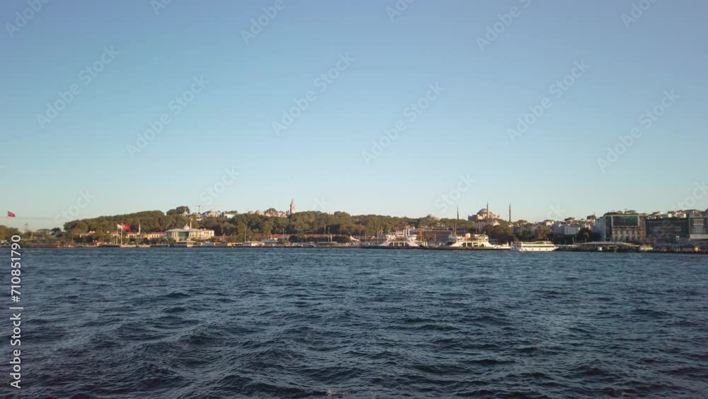 Evening, cinematic slow-mo, a mesmerizing view of Sarayburnu from a ferry on the Golden Horn in Istanbul. The shot features the Hagia Sophia, the cityscape, and Sirkeci Port. Evening, cinematic slow-mo, a mesmerizing view of Sarayburnu from a ferry on the Golden Horn in Istanbul. The shot features the Hagia Sophia, the cityscape, and Sirkeci Port.
