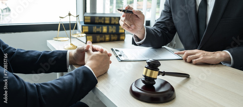 Male lawyer working on documents contract papers of the important case with the business customer and wooden gavel, brass scale in office