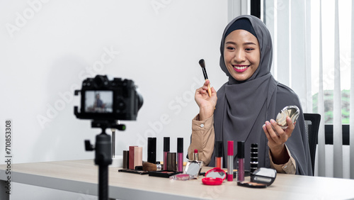 Asian muslim woman beauty blogger applies skin powder with brush