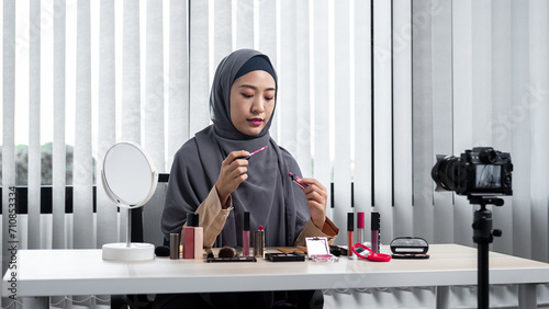 Asian muslim woman beauty blogger recommend and to review pink lipstick while recording vlog video