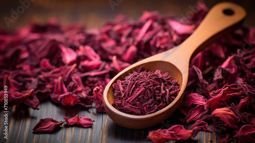 dry hibiscus in a wooden spoon. dried hibiscus petals on a wooden table. hibiscus tea.
