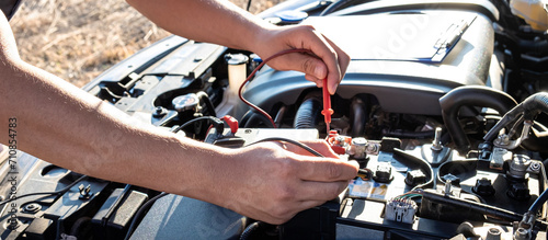 Mechanic checking a car engine with digital voltmeter testing battery capacity, Repair service and Maintenance car battery