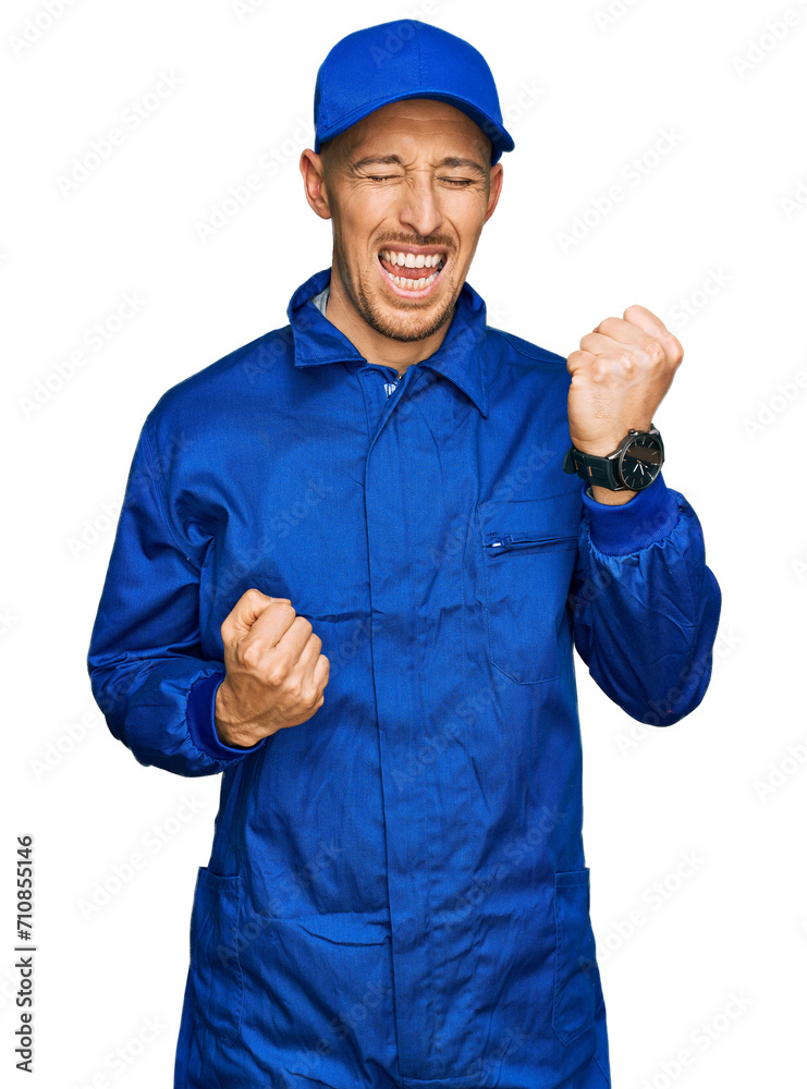 Bald man with beard wearing builder jumpsuit uniform celebrating surprised and amazed for success with arms raised and eyes closed. winner concept. Bald man with beard wearing builder jumpsuit uniform celebrating surprised and amazed for success with arms raised and eyes closed. winner concept.