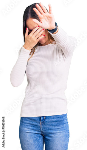 Beautiful brunette young woman wearing casual white sweater and glasses covering eyes with hands and doing stop gesture with sad and fear expression. embarrassed and negative concept.