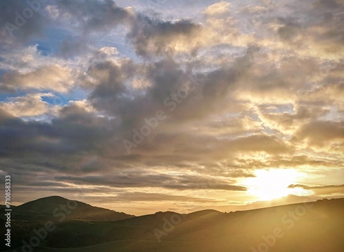 sunset colors paint the sky, as clouds float gracefully over the mountains