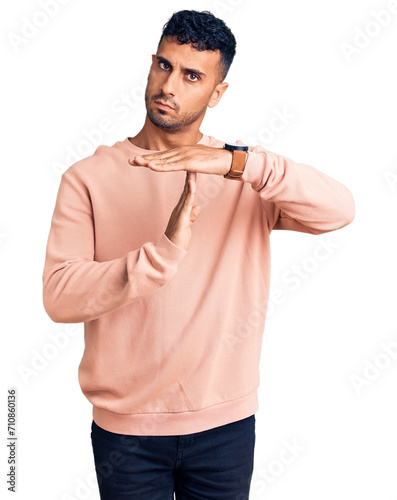 Young hispanic man wearing casual clothes doing time out gesture with hands, frustrated and serious face