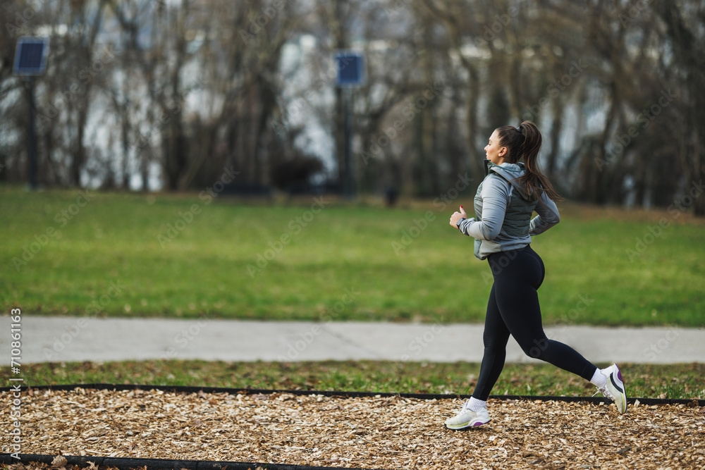 Woman Running in Park With Trees in Background Woman Running in Park With Trees in Background