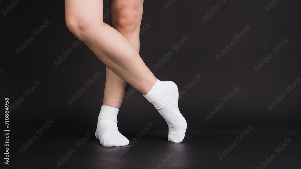 Fototapeta premium Asian Male legs wear white sock on black background.