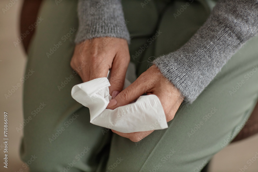 Top view closeup of unrecognizable senior woman holding tissue in hands during therapy session and crying, copy space