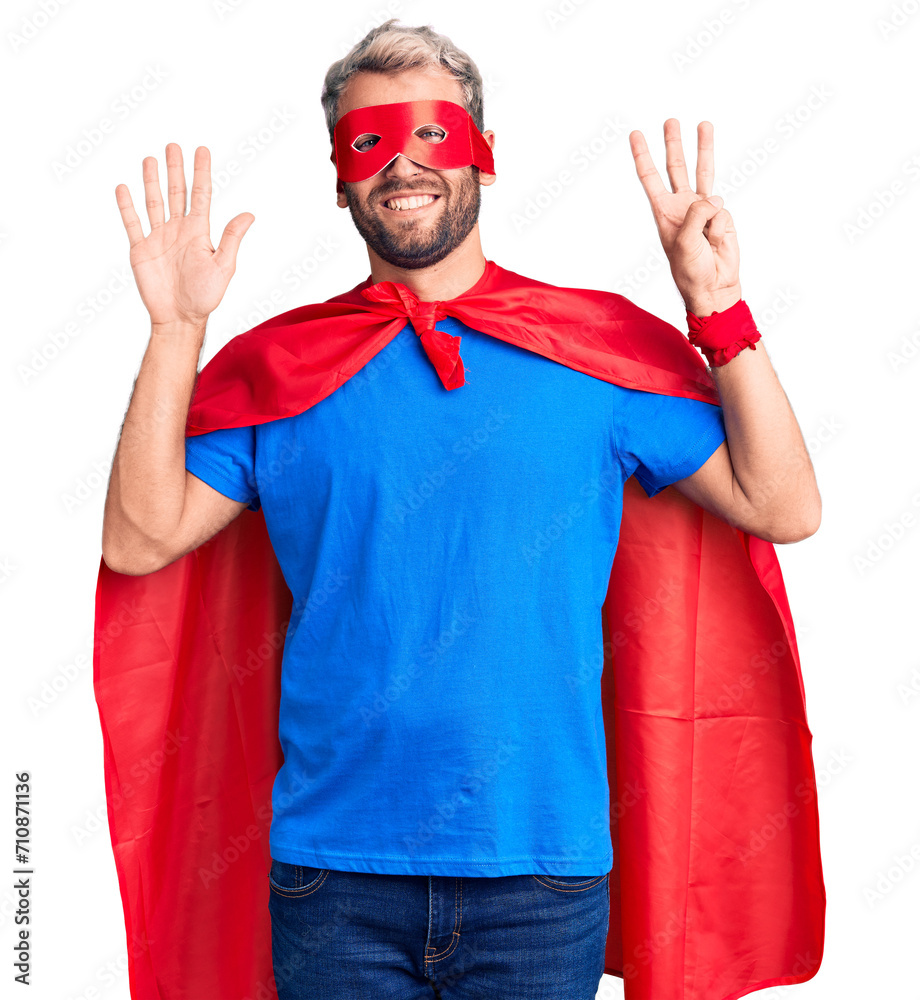 Young blond man wearing super hero custome showing and pointing up with fingers number eight while smiling confident and happy. Young blond man wearing super hero custome showing and pointing up with fingers number eight while smiling confident and happy.