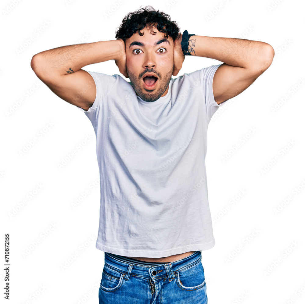 Hispanic young man with beard wearing casual white t shirt crazy and scared with hands on head, afraid and surprised of shock with open mouth Hispanic young man with beard wearing casual white t shirt crazy and scared with hands on head, afraid and surprised of shock with open mouth