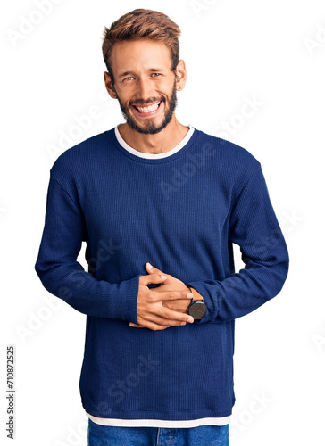 Handsome blond man with beard wearing casual sweater smiling and laughing hard out loud because funny crazy joke with hands on body.