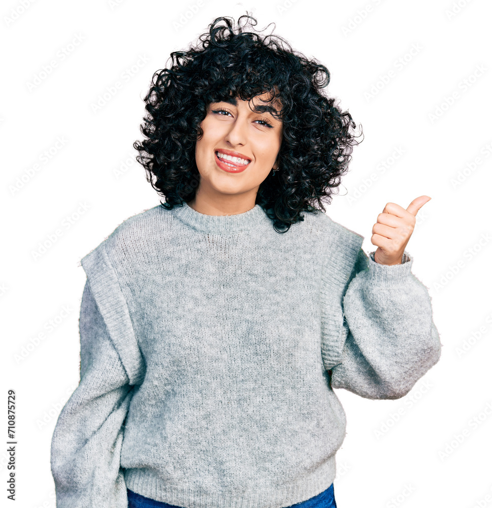 Young middle east girl wearing casual clothes smiling with happy face looking and pointing to the side with thumb up. Young middle east girl wearing casual clothes smiling with happy face looking and pointing to the side with thumb up.