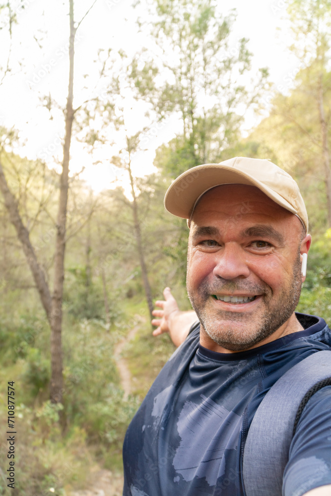 Happy hiker takes a phot selfie showing the landscape.