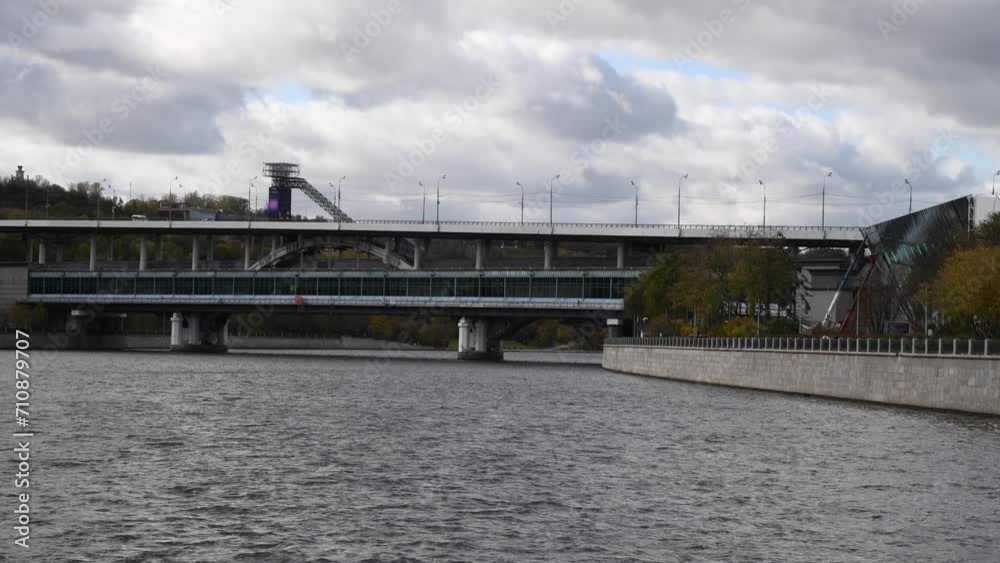 City view from tour boat sailing next to bridge with railway station on Moskva river in a cloudy autumn day in Moscow, Russia. Soft focus. Real time handheld video. Water travel theme. City view from tour boat sailing next to bridge with railway station on Moskva river in a cloudy autumn day in Moscow, Russia. Soft focus. Real time handheld video. Water travel theme.
